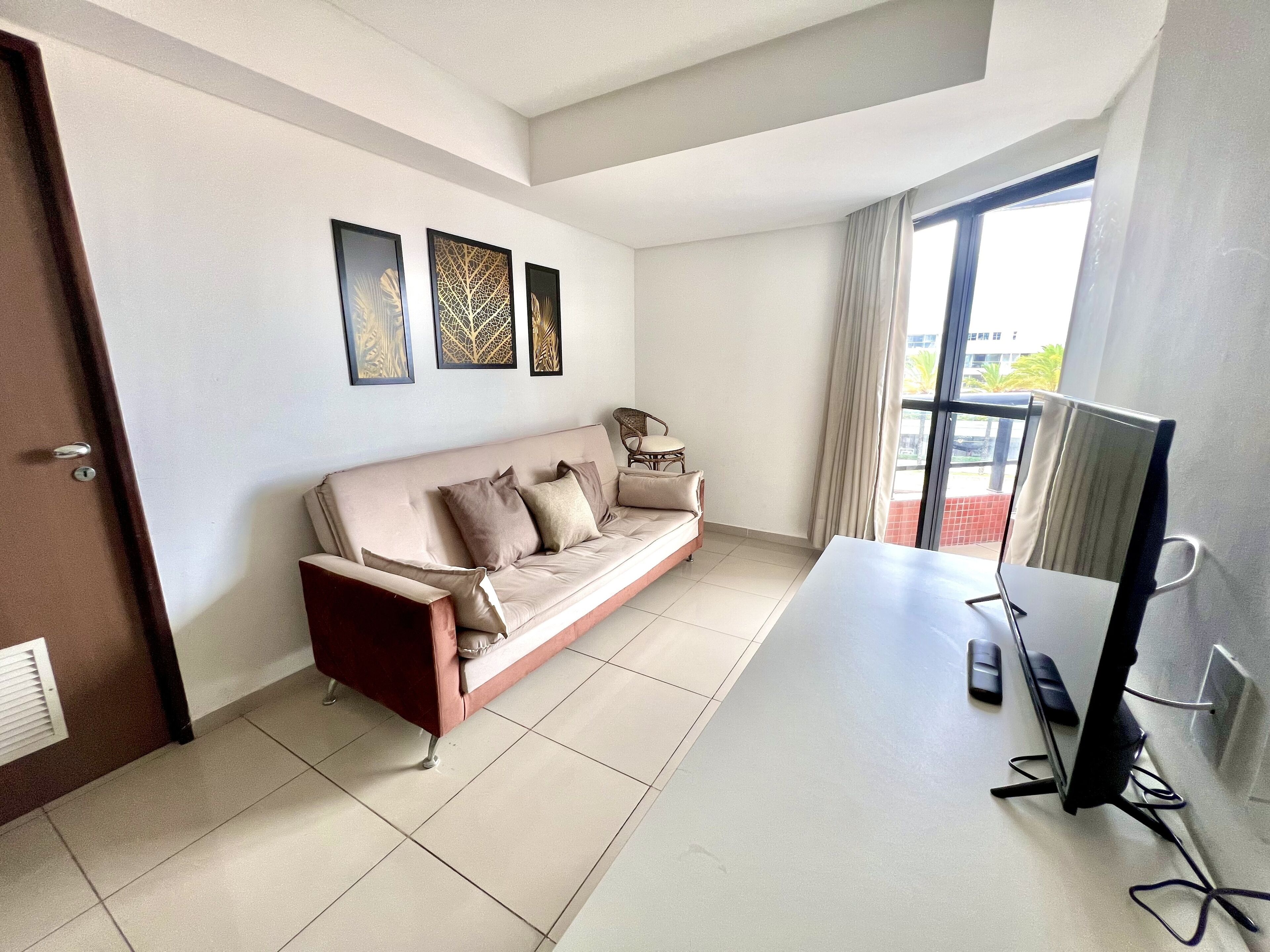 A modern living room with a beige sofa, a flat-screen TV, and artwork on the wall.