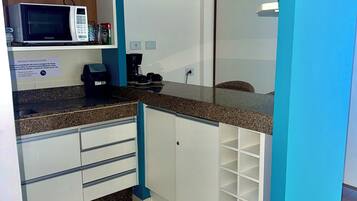 A kitchen with white cabinets, a microwave, a coffee maker, and a sink.
