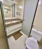 Un bagno con lavabo in granito, uno specchio, un porta asciugamani, un asciugacapelli e un water.