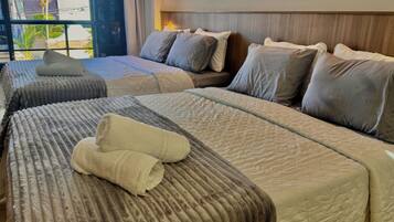A hotel room with two beds, each with a headboard, and a large window with a view of palm trees.