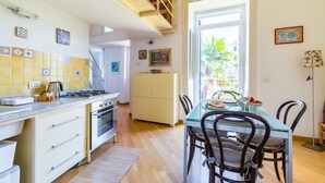 A modern kitchen with a dining area, featuring a built-in oven, a coffee maker, and a dining table with chairs. - Montemiletto a Panoramic Nest by Napoliapartments (Napoli)