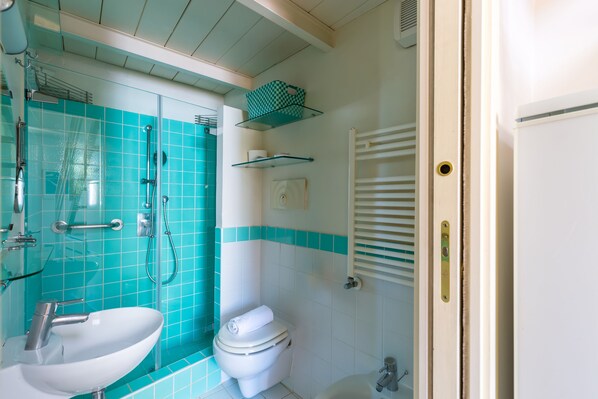 Un baño con cabina de ducha de vidrio, un lavabo blanco y un inodoro.