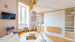 A modern living room with a sofa, a TV, a staircase, and a built-in wardrobe. - Montemiletto a Panoramic Nest by Napoliapartments (Napoli)