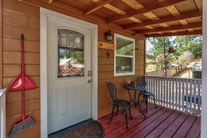 A wooden porch with a white door, a red broom, and two metal chairs. -  Hidden gem in green heaven, getaway to Bass Lake & Yosemite (Oakhurst)