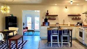 Een moderne keuken met een eethoek, met een centraal eiland, hanglampen en inbouwplanken.