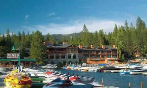 Boats docked at the marina, surrounded by evergreen trees and a classic hotel.