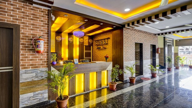 A hotel reception area with a brick facade, a reception desk, and a modern ceiling design. - Itsy Hotels Galaxy Park (Hyderabad)