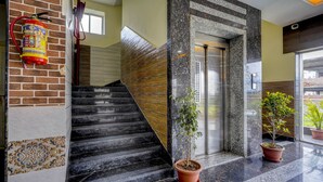 A staircase with a fire extinguisher, an elevator, and potted plants. - Itsy Hotels Galaxy Park (Hyderabad)