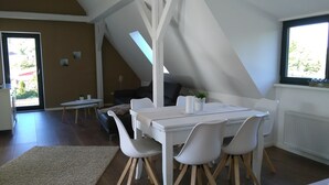 Un comedor moderno y bien iluminado con una mesa y sillas blancas, un tapete pequeño y vistas al exterior a través de una ventana.
