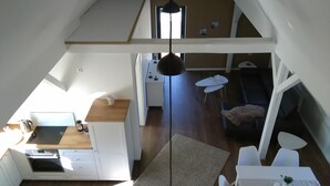Una cocina compacta con estufa, gabinetes blancos y un comedor con mesa y sillas.