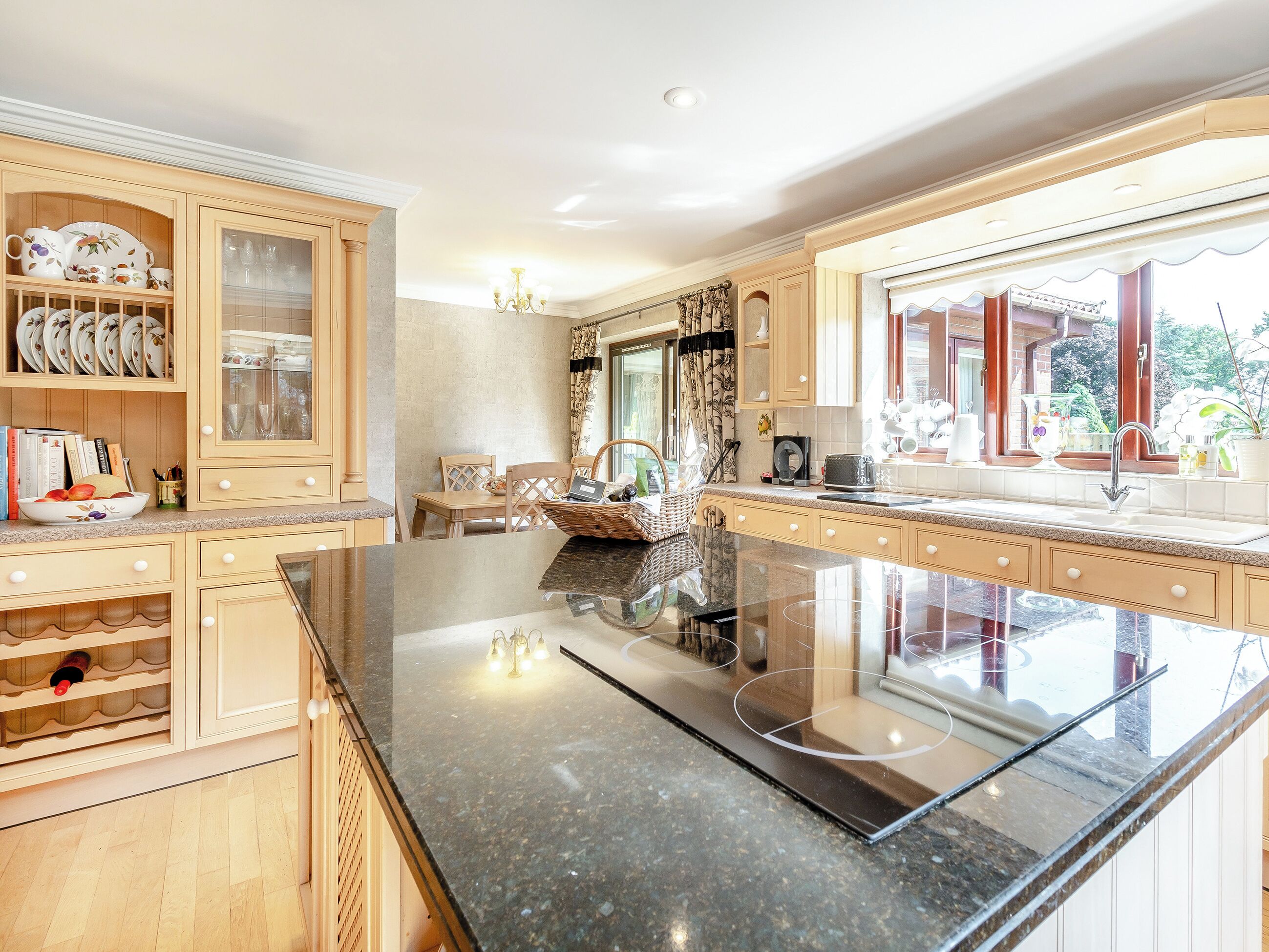 A spacious kitchen with a large island, wooden cabinetry, and a view of the outdoors through a window.