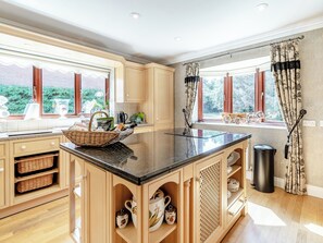 A kitchen with wooden cabinets, a black countertop, and a window with a view of trees.