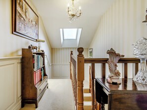 A hallway with a wooden staircase, a chandelier, a bookshelf, and a framed picture on the wall. - 3 bedroom accommodation in Ottringham, near Withernsea (Ottringham, near Withernsea)