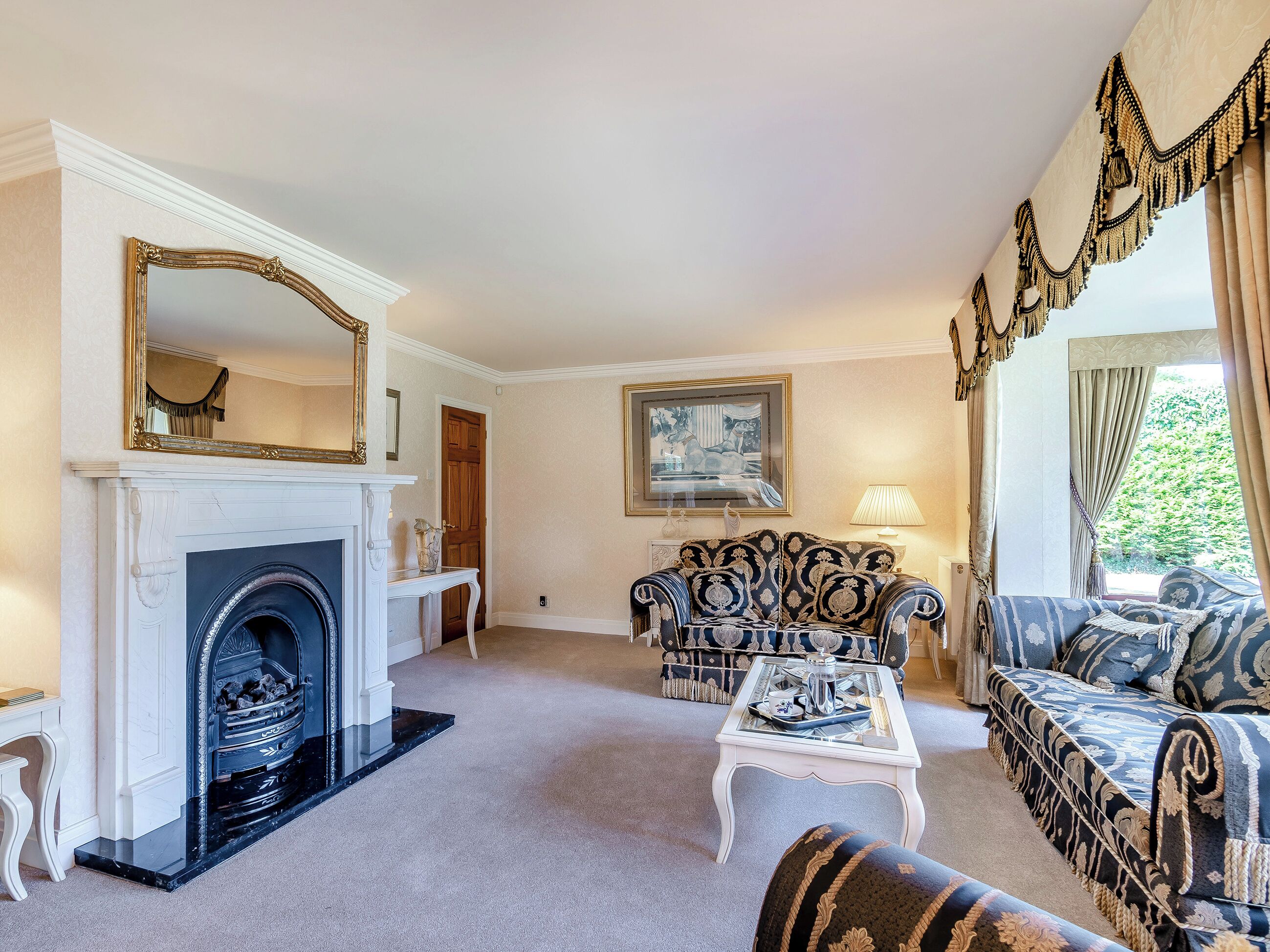 A living room with a fireplace, a sofa, a coffee table, and a large mirror.