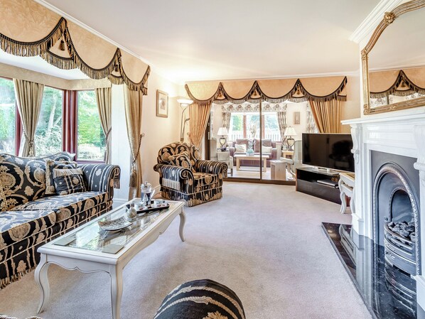 A spacious living room with a fireplace, a television, and a sofa set.