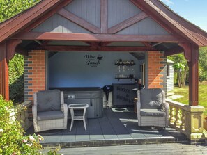 A covered outdoor seating area with wicker furniture and a bar.