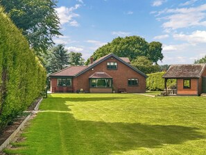 A two-story brick house with a well-maintained lawn and a small garden area.