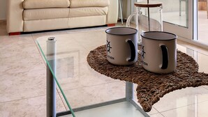 A living room with a beige sofa, a glass coffee table with two mugs, a ceiling fan, and a view of the outside balcony. - Apartment with mountain and sea views, parking (Cabo de Palos)