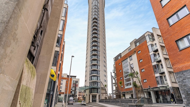 Un edificio alto y moderno con fachada curva, rodeado de otros edificios contemporáneos.