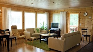 Una habitación acogedora tipo cabaña con paredes de madera, un sofá, un televisor y un comedor.