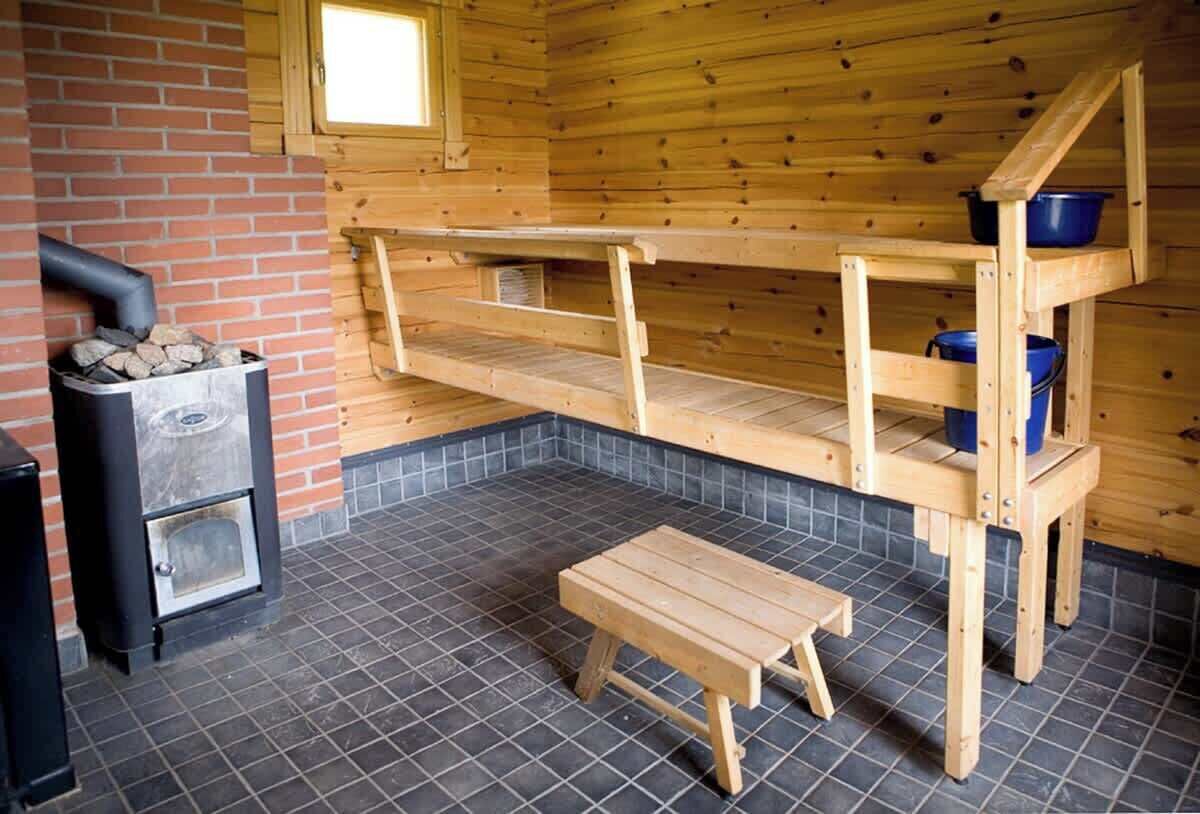 Una cabaña de madera con chimenea, un banco de madera y una pequeña mesa.