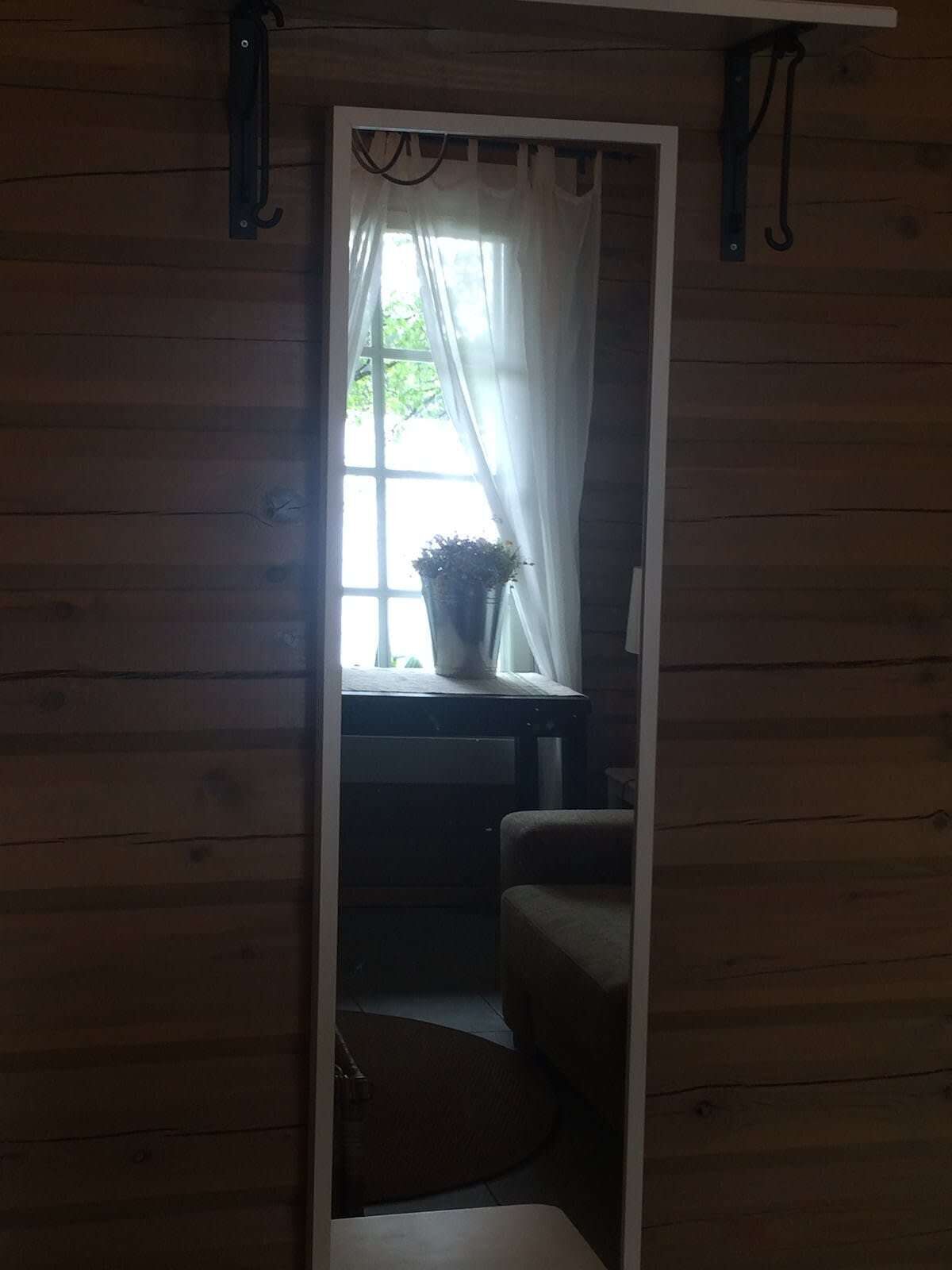 Un étroit passage donne accès à une pièce avec une fenêtre, une plante en pot et une chaise.