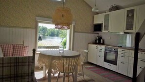 Een gezellige keuken met een eethoek, uitzicht op een meer en een trap naar een slaapkamer op een entresol.