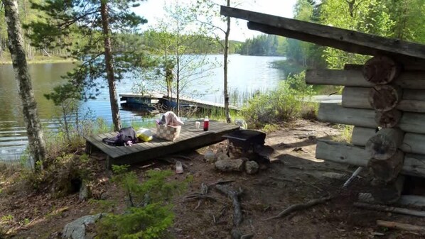 A rustic cabin with a dock extending into a lake, surrounded by trees.