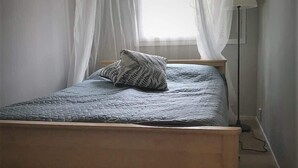 Una cama con dosel, un cojín estampado y una lámpara de noche.