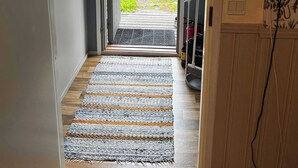 A hallway leading to a door with a view of a lake and forest.
