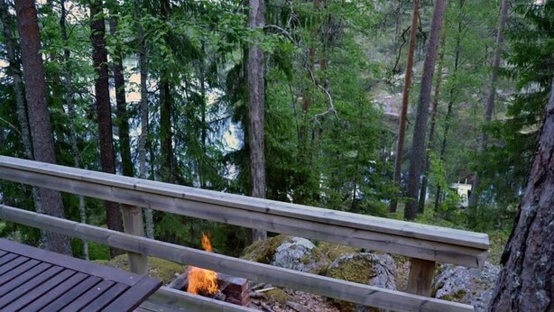 A wooden deck with a fire pit surrounded by trees. - Enchanting cottage in the woods, by the lake (Orivesi)