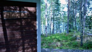 A wooden cabin with a sign reading "MINTIC" and a view of a dense forest. - Silent, private cottage by lake,  sauna and boat (Orivesi)