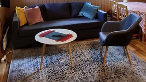 A cozy living room with a dark sofa, colorful cushions, a round coffee table, and a patterned rug. - Silent, private cottage by lake,  sauna and boat (Orivesi)