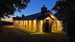 Ein Haus mit einer Steinfassade, einem dunklen Dach und einem gut beleuchteten Eingang.