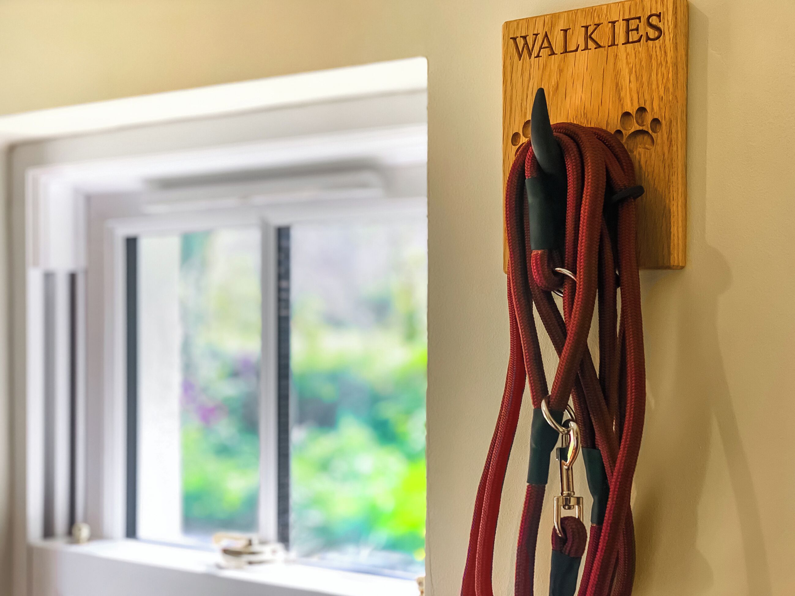 A wooden plaque with the word "WALKIES" and a dog leash hanging on it.