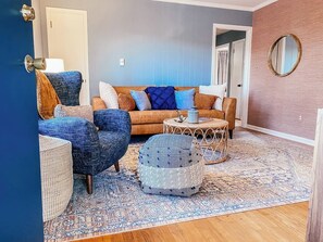 Ein Wohnzimmer mit einer Couch, zwei Sesseln, einem Couchtisch und einem gemusterten Teppich.
