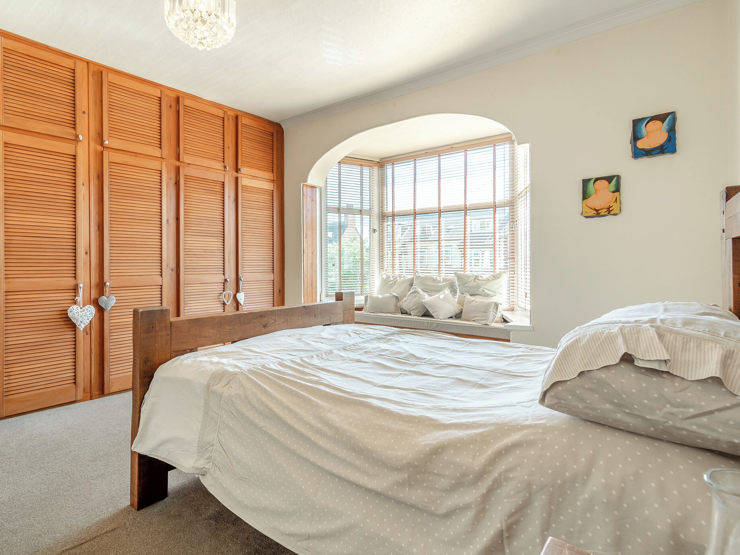 Un dormitorio con una cama grande, un armario de madera y una ventana con persianas.
