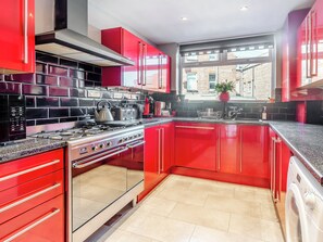 Een moderne keuken met rode kastjes, een roestvrijstalen fornuis en een groot raam.