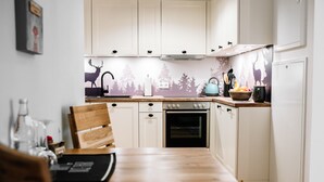 Eine Küche mit weißen Schränken, einem Holztisch und einer Wanddekoration mit Hirschen und Bäumen.