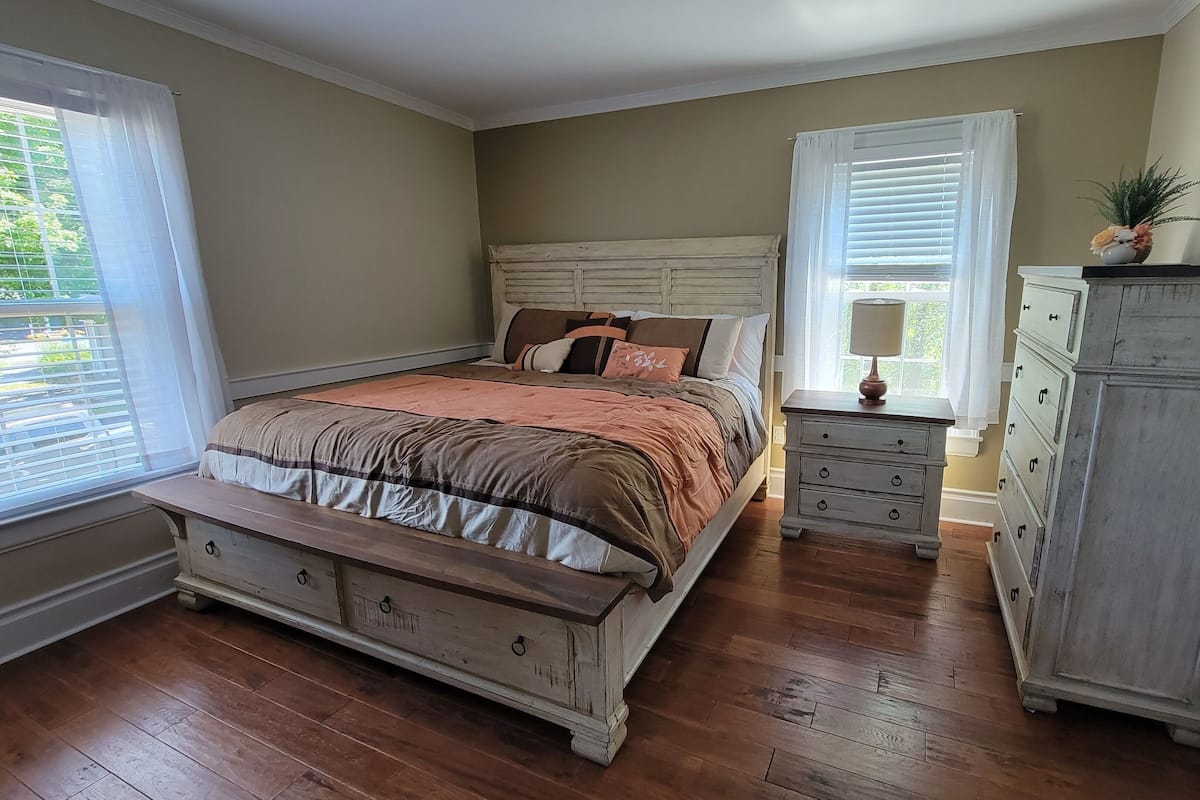 A bedroom with a wooden bed, a dresser, and a nightstand.