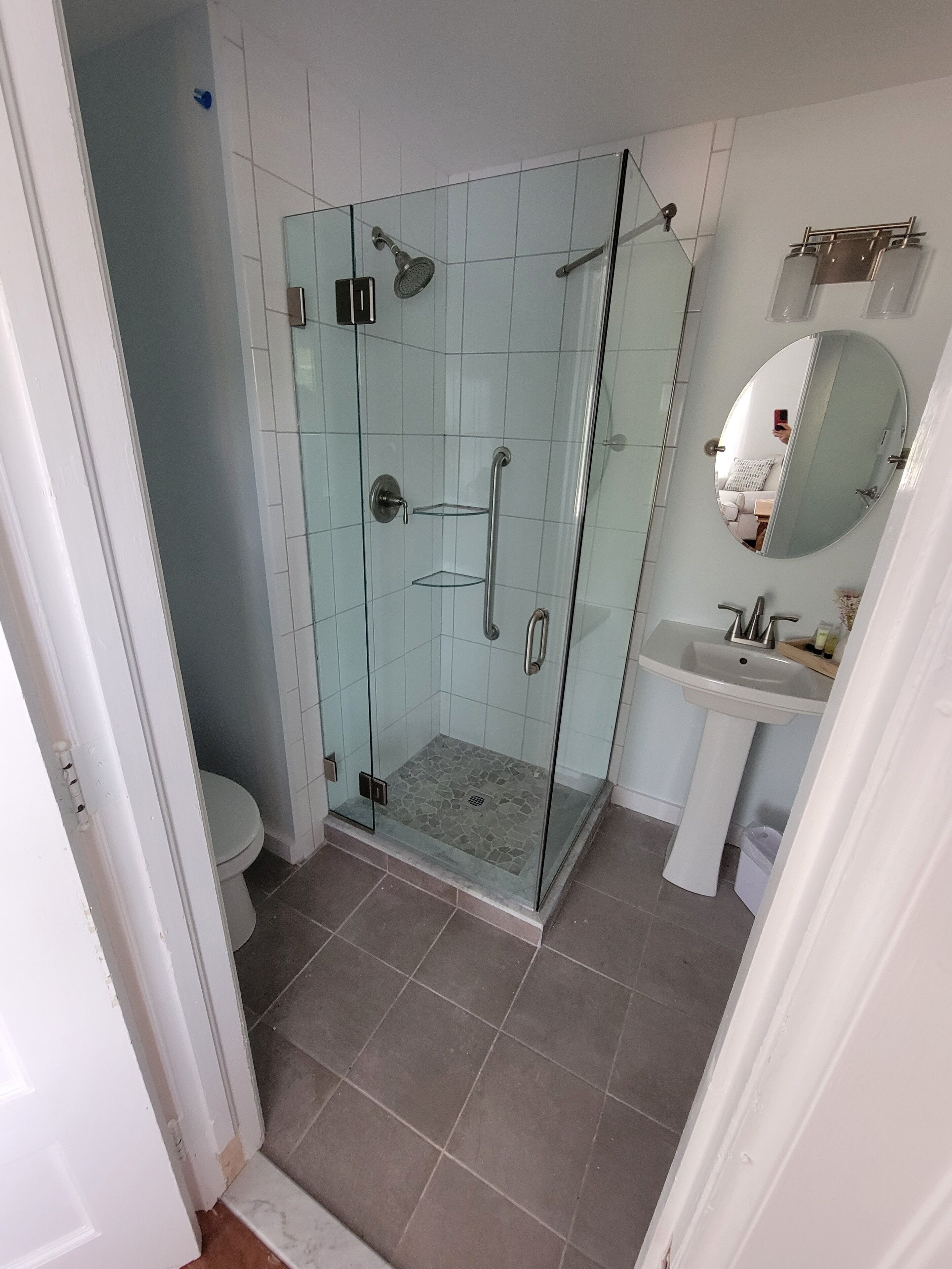 Un bagno con doccia vetrata, un water e un lavandino con specchio.