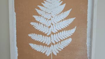 Une œuvre d’art encadrée représentant une fougère sur un fond brun texturé.