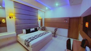 A modern bedroom with a large bed, bedside lamps, a wooden headboard, a desk, and a wardrobe. - OLYMPUS HOTEL & SUITES (Ibadan)