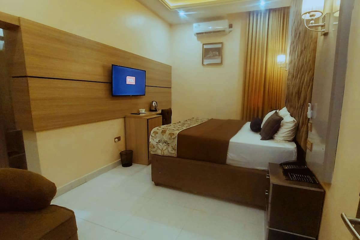 A modern hotel room with a bed, a TV, a desk, and a chair.