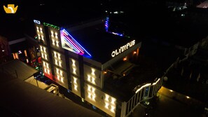 A building with a sign reading "OLYMPIUS" and a brightly lit facade.