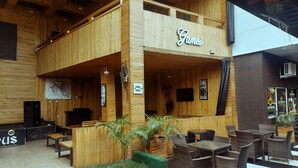 A wooden building with a sign reading "Games" and a "Free WiFi" sign. There are wicker tables and chairs outside. - OLYMPUS HOTEL & SUITES (Ibadan)