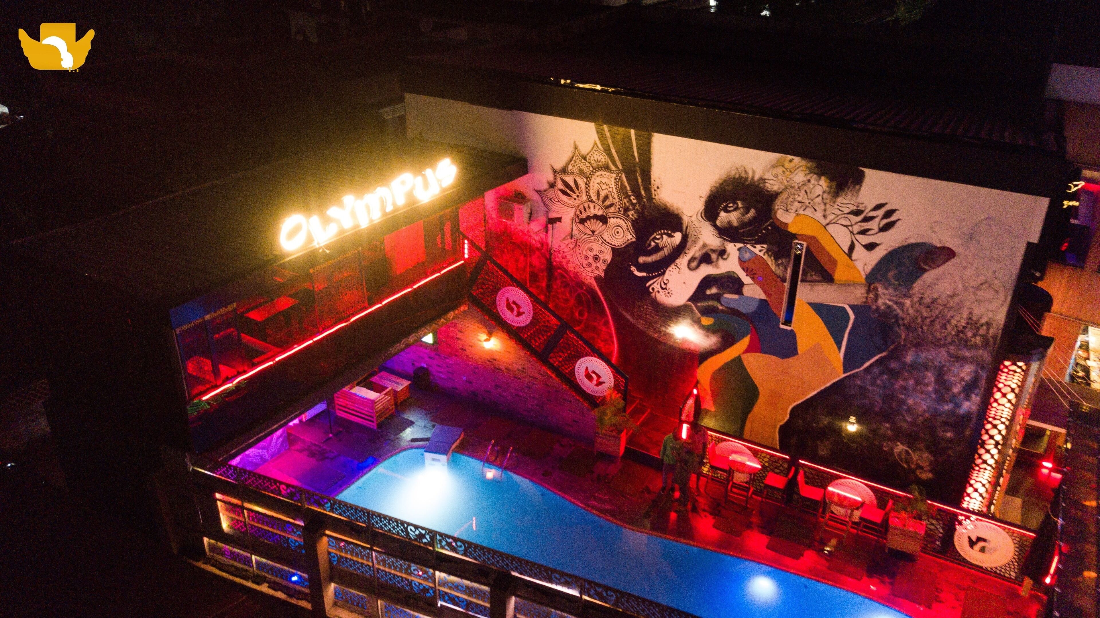 A bar area with a neon sign, a mural, and a pool.