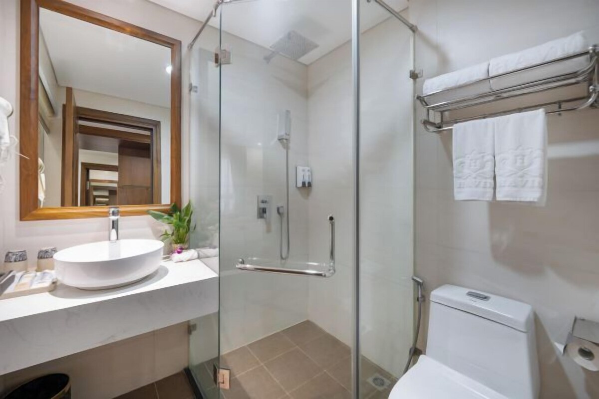 Un baño moderno con ducha de vidrio, un lavamanos blanco y un inodoro.