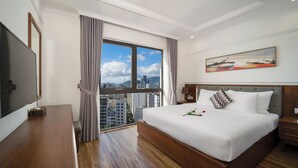 Une chambre d’hôtel avec un grand lit, une télévision, un bureau en bois et une vue sur la ville par la fenêtre.