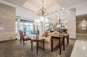 A spacious living room with a chandelier, a sofa set, a coffee table, and a dining table.